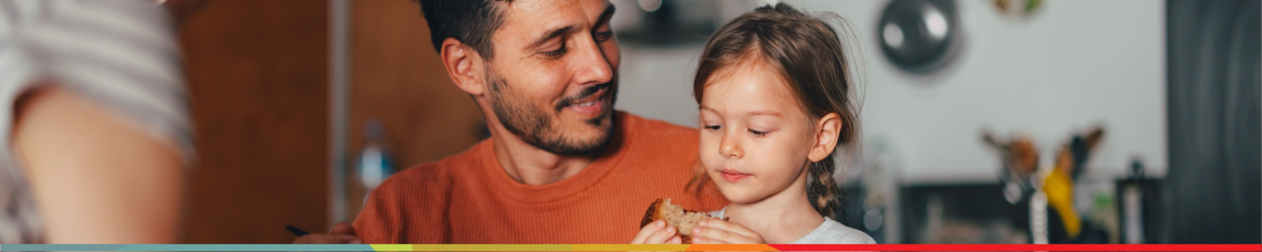 Happy father and young daughter eating breakfast in kitchen