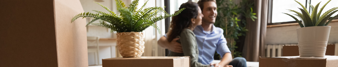 Young smiling couple surrounded by boxes in their new home