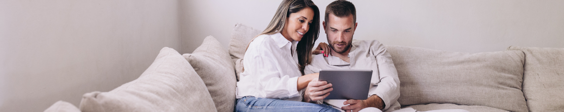 Young couple sitting on couch calculating their down payment