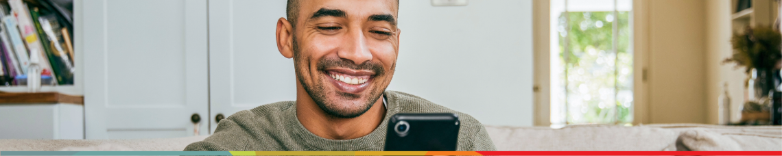 Man smiling on couch looking at phone in home